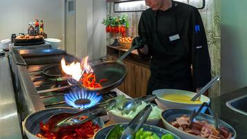 Una cocina con estufa a gas, un wok sobre fuego y varios cuencos con comida.