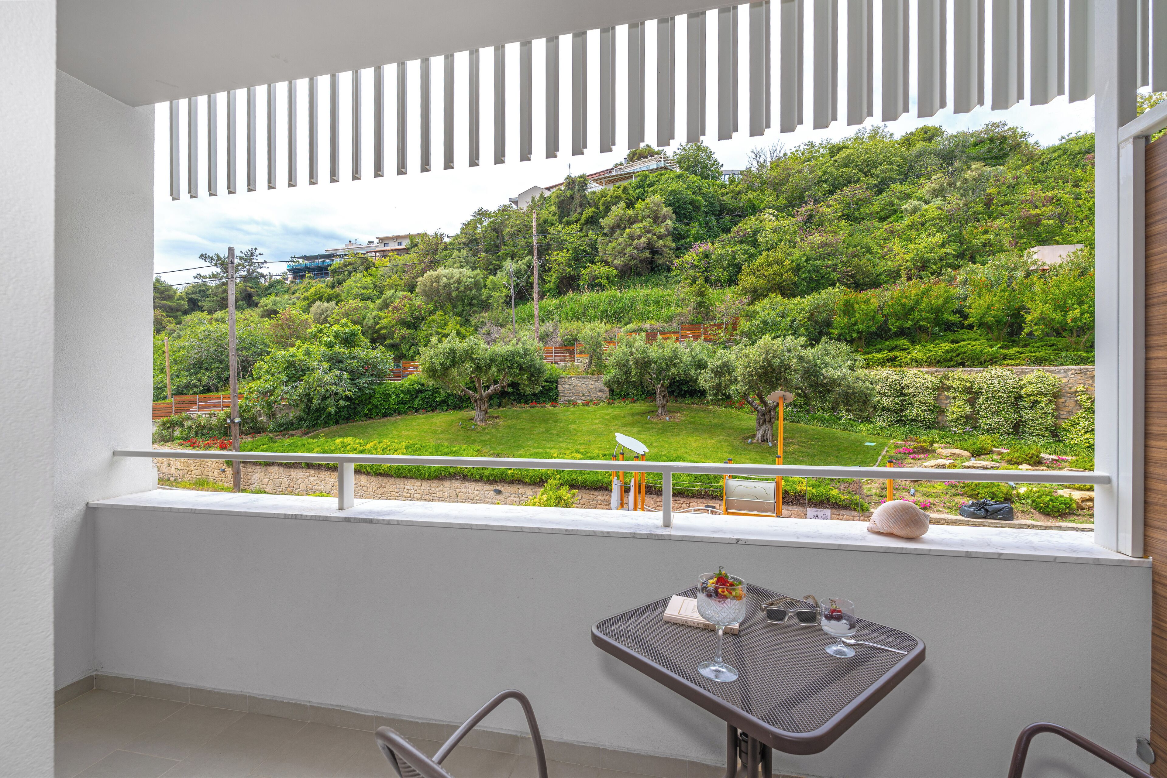 Un balcón con vistas a un jardín exuberante y una ladera.