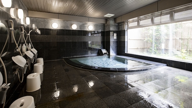 Ein modernes Badezimmer mit einer großen Badewanne, mehreren Pissoirs und einem Fenster, das für natürliches Licht sorgt.