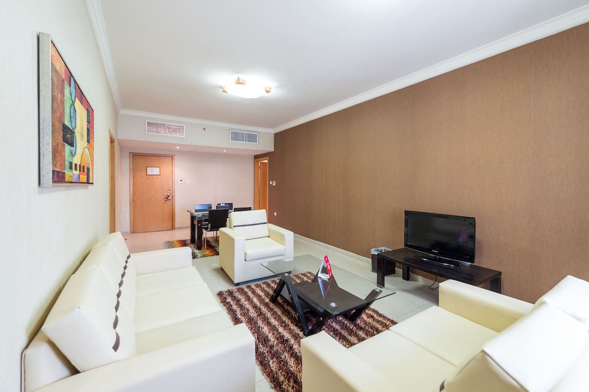 Een moderne woonkamer met witte banken, een flatscreen televisie en een salontafel.