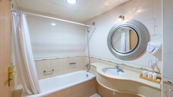 Une salle de bain équipée d’une baignoire, d’un lavabo, d’un miroir et d’un rideau de douche.