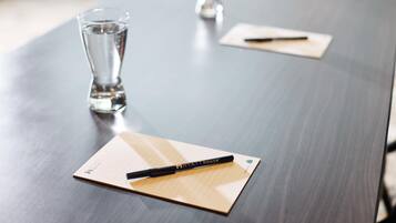 Een vergadertafel met notitieboek en pen, een glas water, en een pen op een notitieblok.