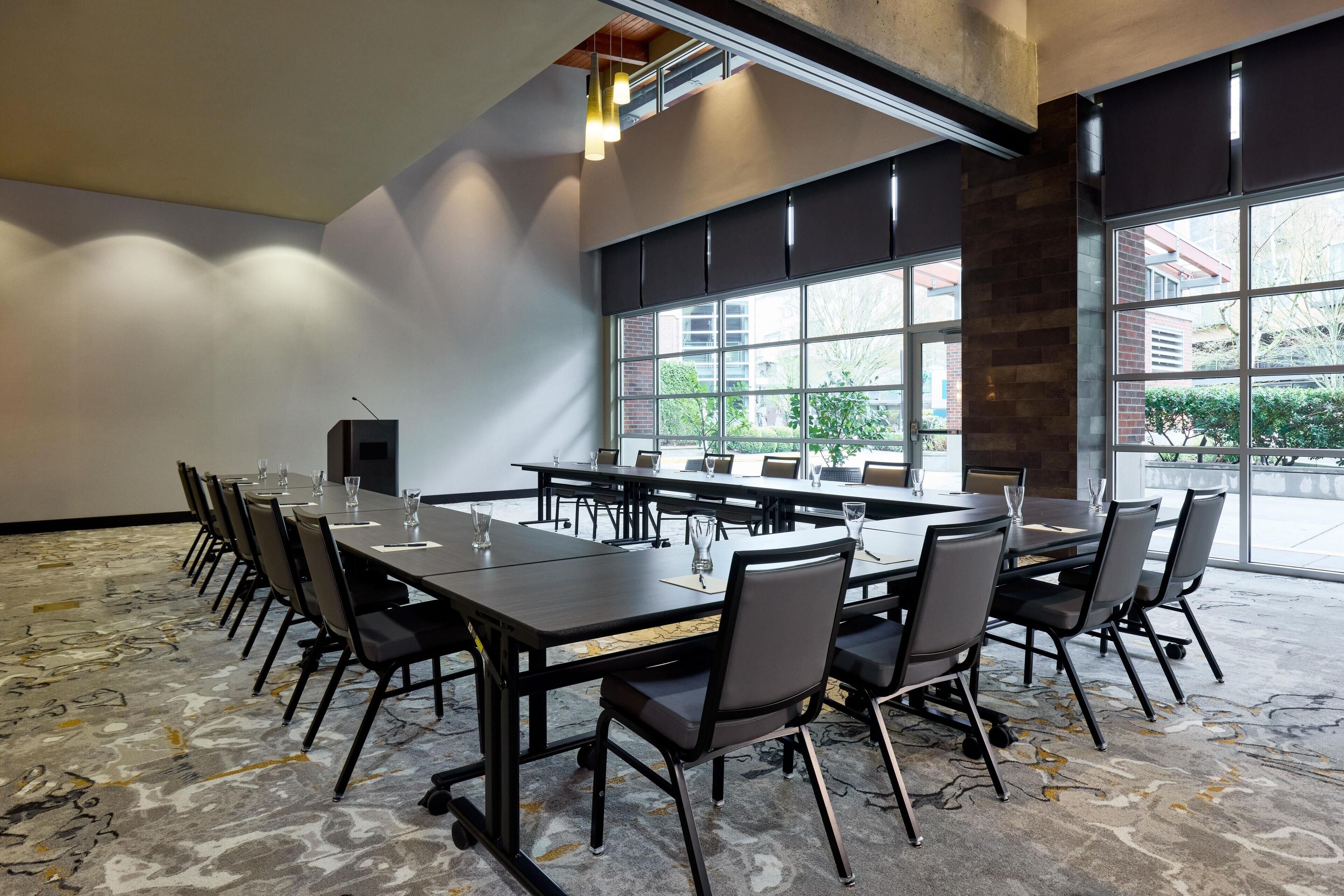 A conference room with a long table, chairs, and a projector screen.