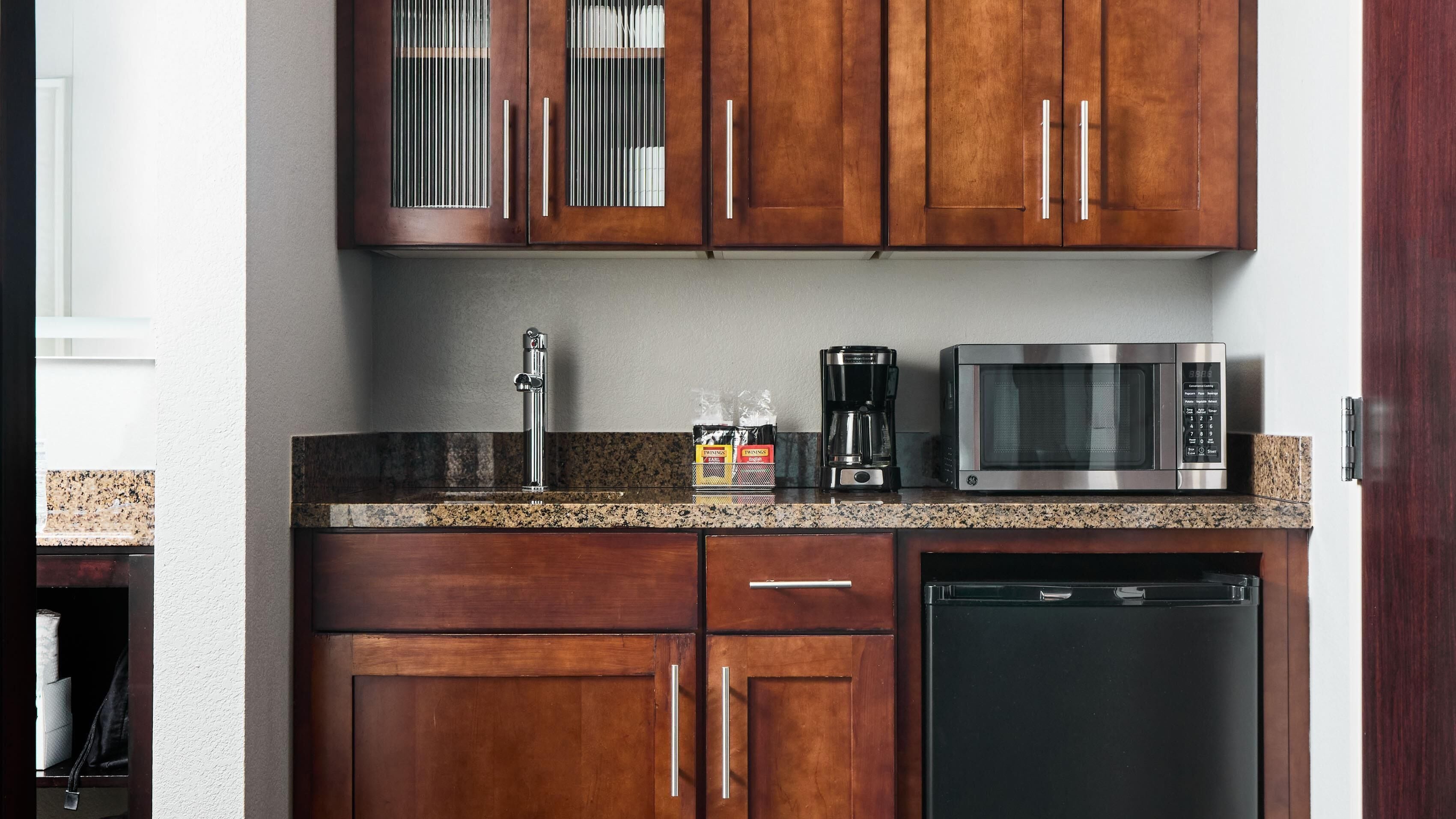 A kitchen with wooden cabinets, a stainless steel microwave, a coffee maker, and a dishwasher.