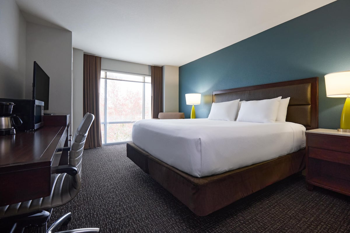 A hotel room with a bed, desk, chair, and a television.