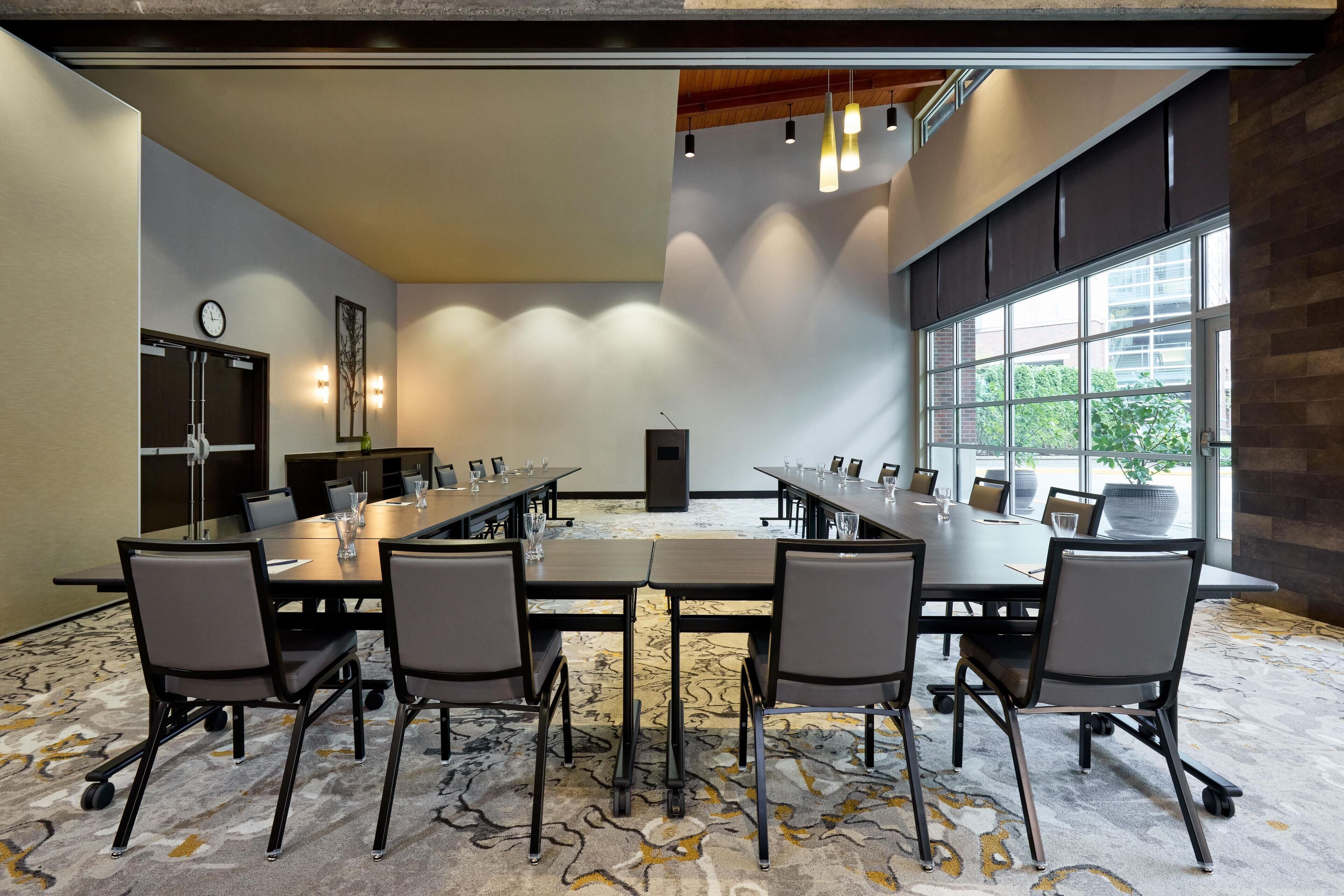 Une salle de conférence avec une grande table, six chaises et une horloge au mur.