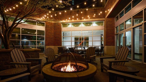 Un área de patio al aire libre con un brasero, asientos e iluminación colgante.