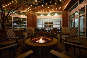 An outdoor patio area with a fire pit, seating, and string lights.
