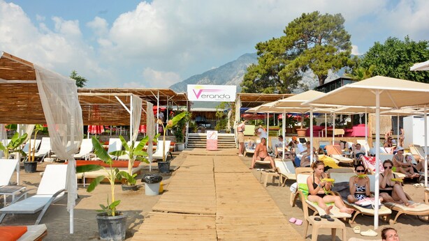 Un resort frente al mar con sillas de madera, sombrillas y plantas en macetas.