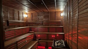 Una sauna con bancos y paredes de madera, equipada con iluminación roja.