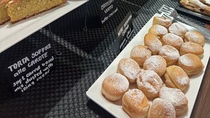 Een bakkerijdisplay met diverse gebakjes en een bord waarop staat dat er een zachte worteltaart is.