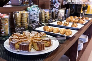 Un buffet proposant une variété de viennoiseries et de desserts, notamment des croissants et un gâteau.