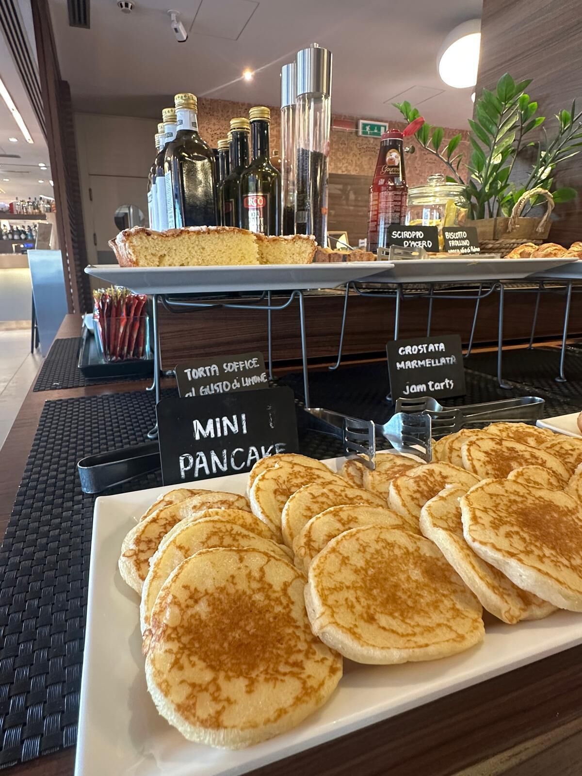 Ein Frühstücksbuffet mit Mini-Pfannkuchen, Biscotti und einem Schild, das ein 'corta soffice' anzeigt.