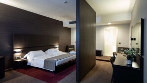 Een moderne hotelkamer met een groot bed, nachtkastjes, een bureau en een spiegel.