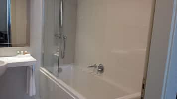 Un baño moderno con ducha de vidrio, lavamanos blanco y espejo.