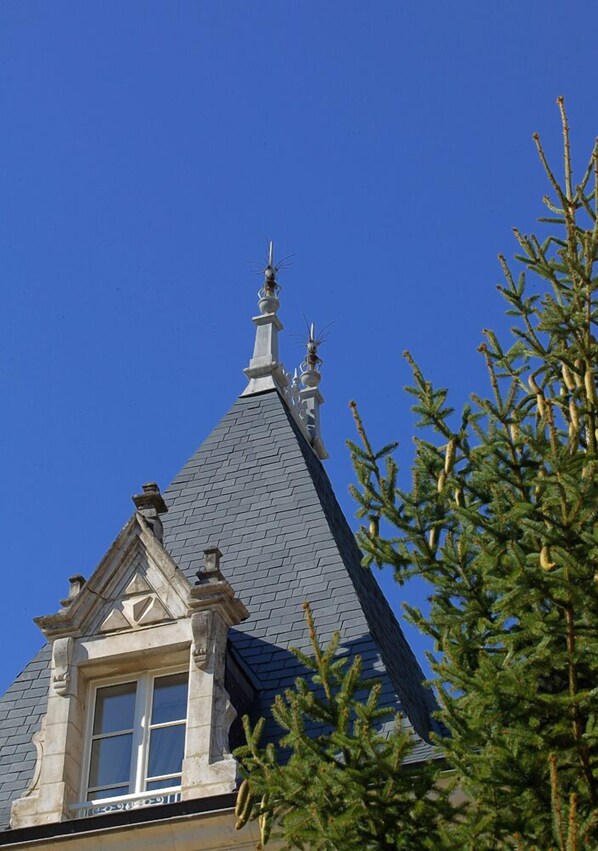 A building with a steeply pitched roof, a prominent chimney, and a window with a stone frame.