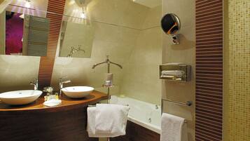 A modern bathroom with two sinks, a bathtub, and a large mirror.
