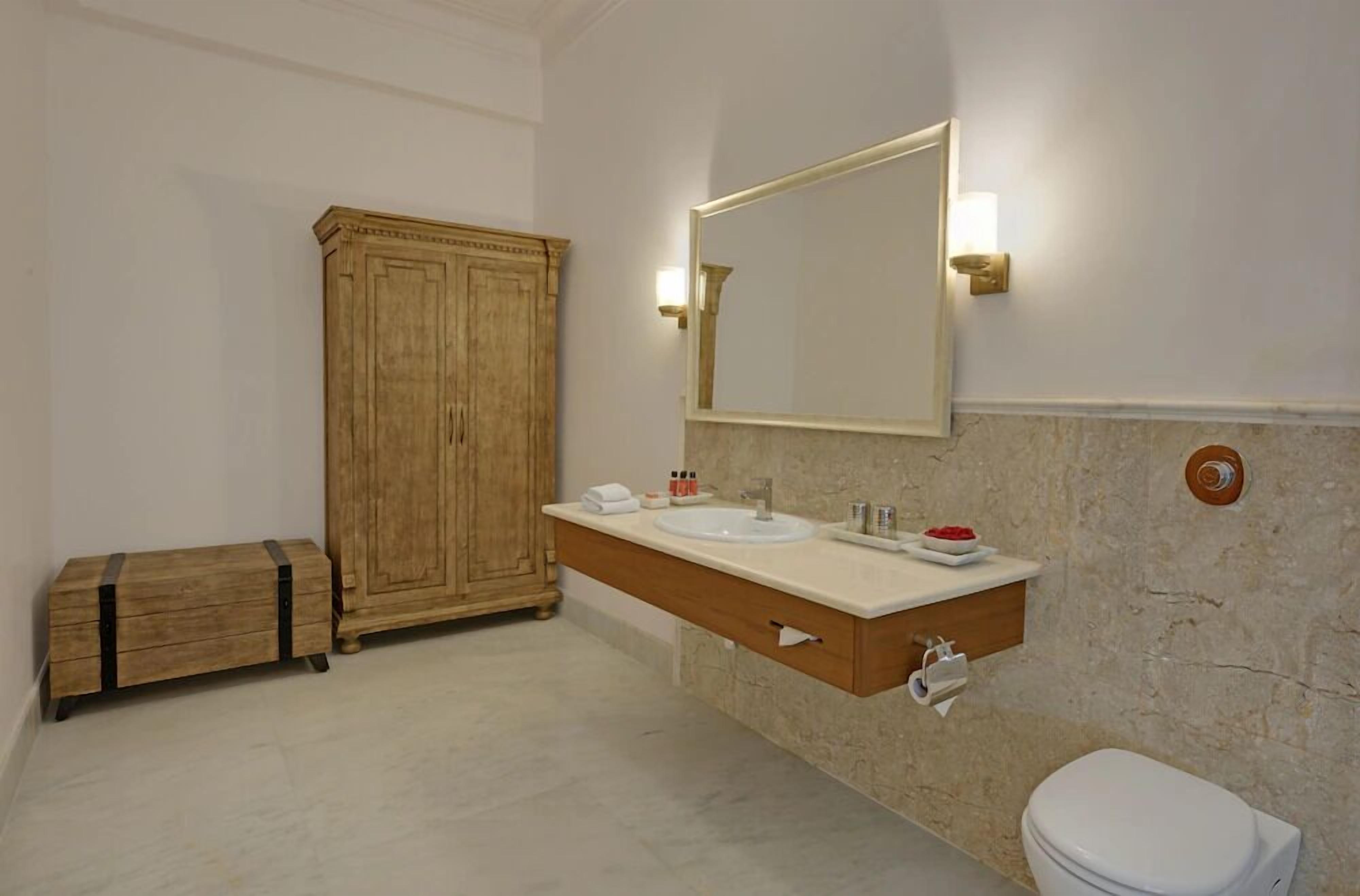 Un baño con un armario de madera, un espejo grande, un lavabo blanco y un inodoro.
