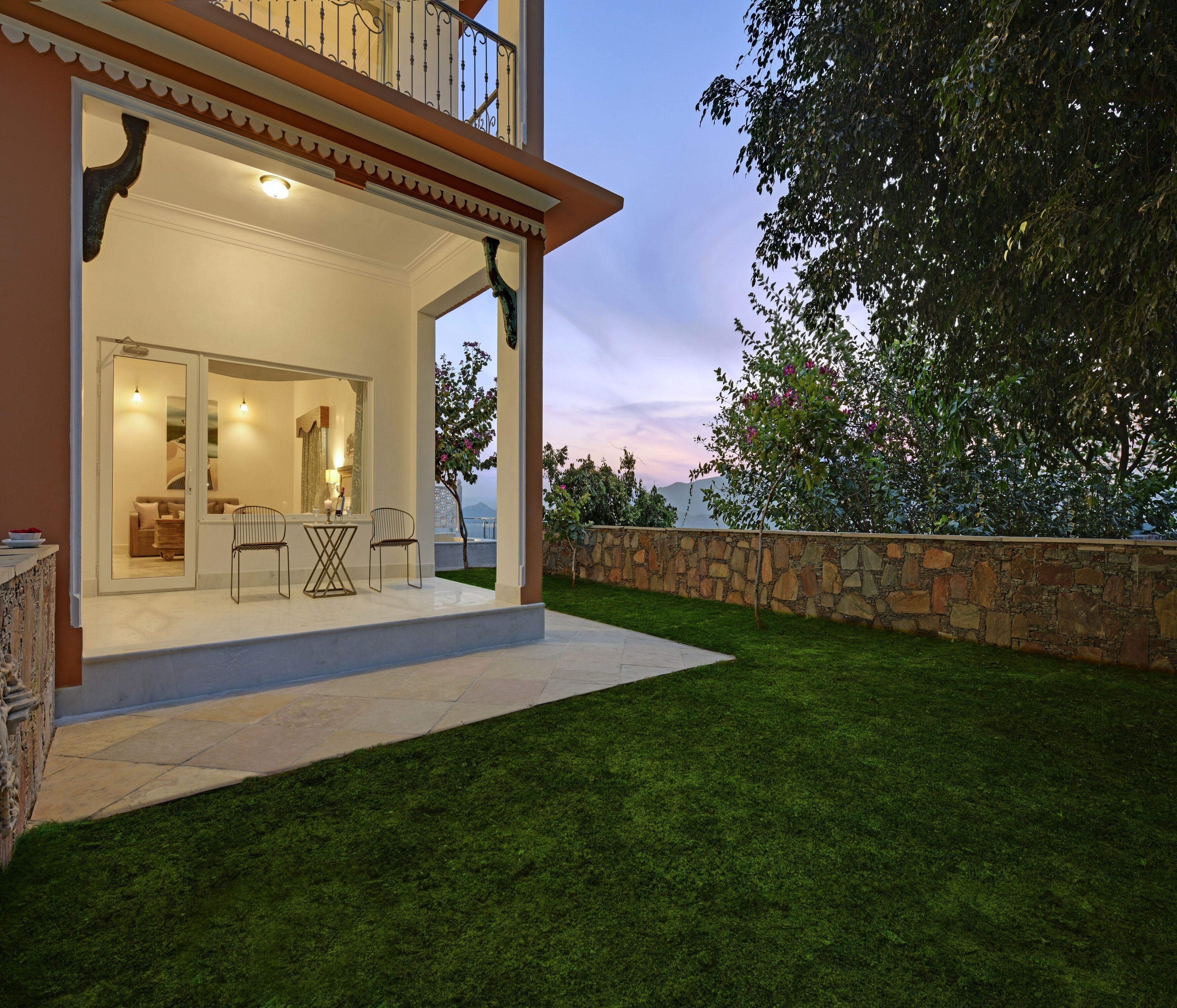 A modern house with a spacious patio, a stone wall, and a view of the surrounding landscape.