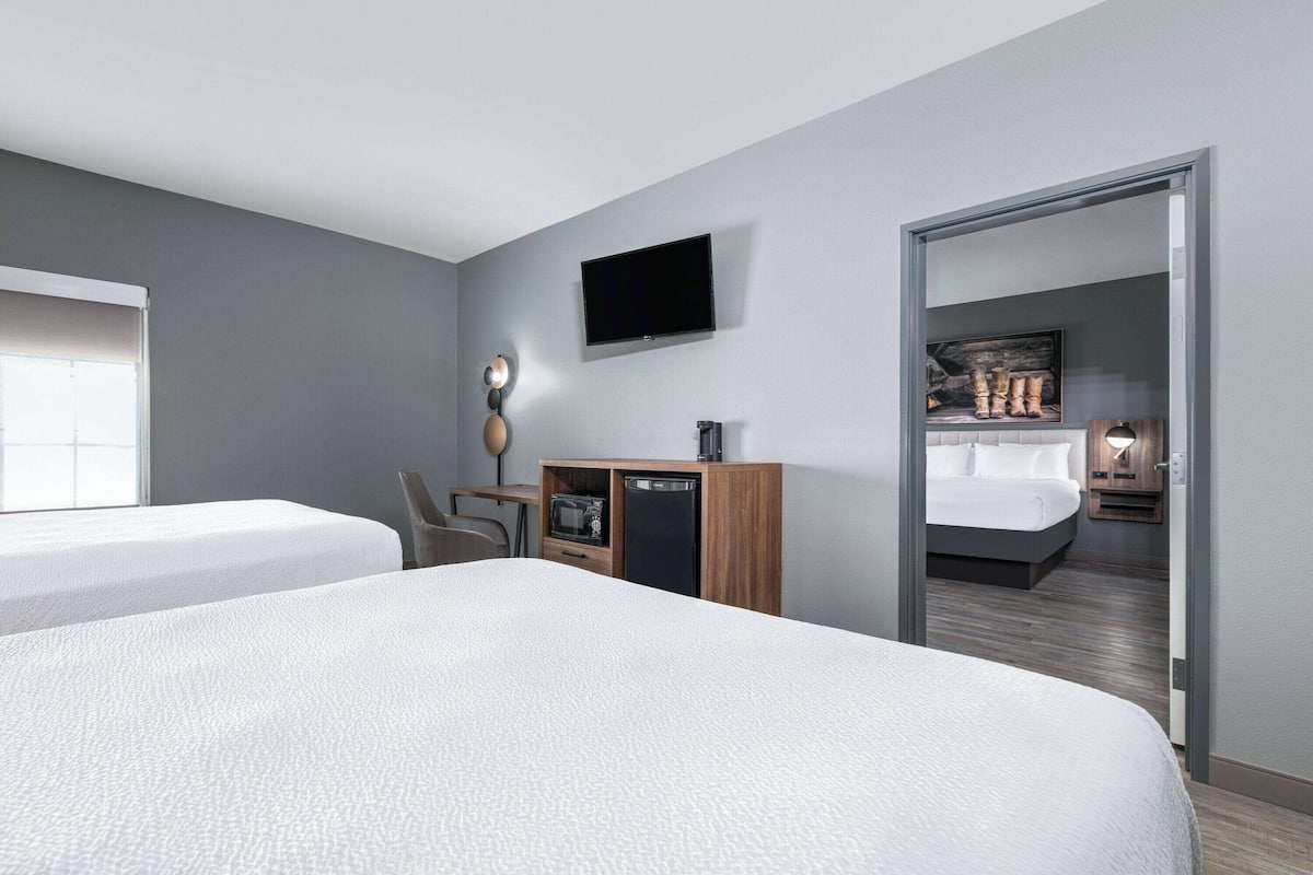 Une chambre d’hôtel avec deux lits, une télévision, un bureau avec une lampe et une armoire.