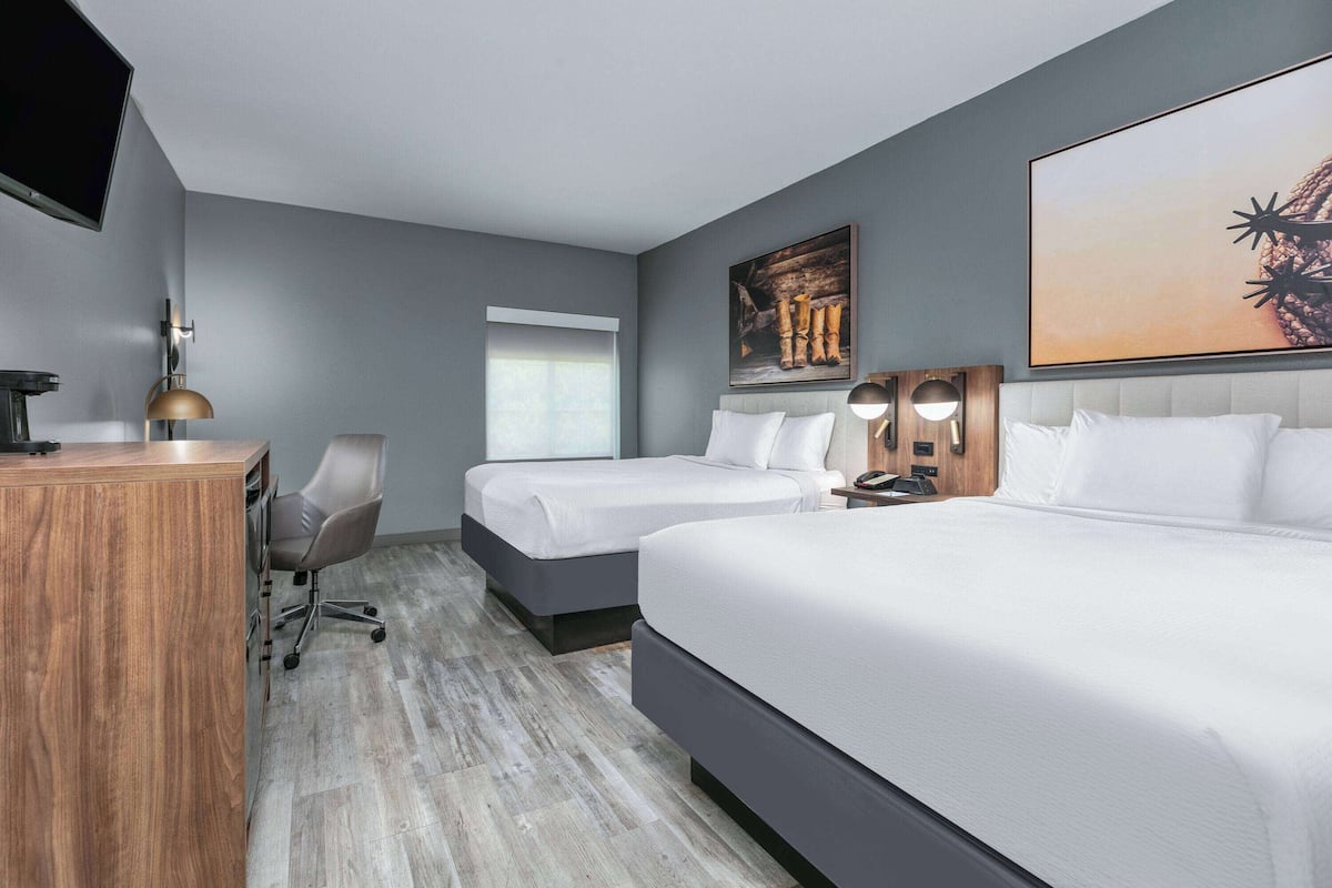 Une chambre d’hôtel avec deux lits, un bureau, une chaise et un téléviseur.