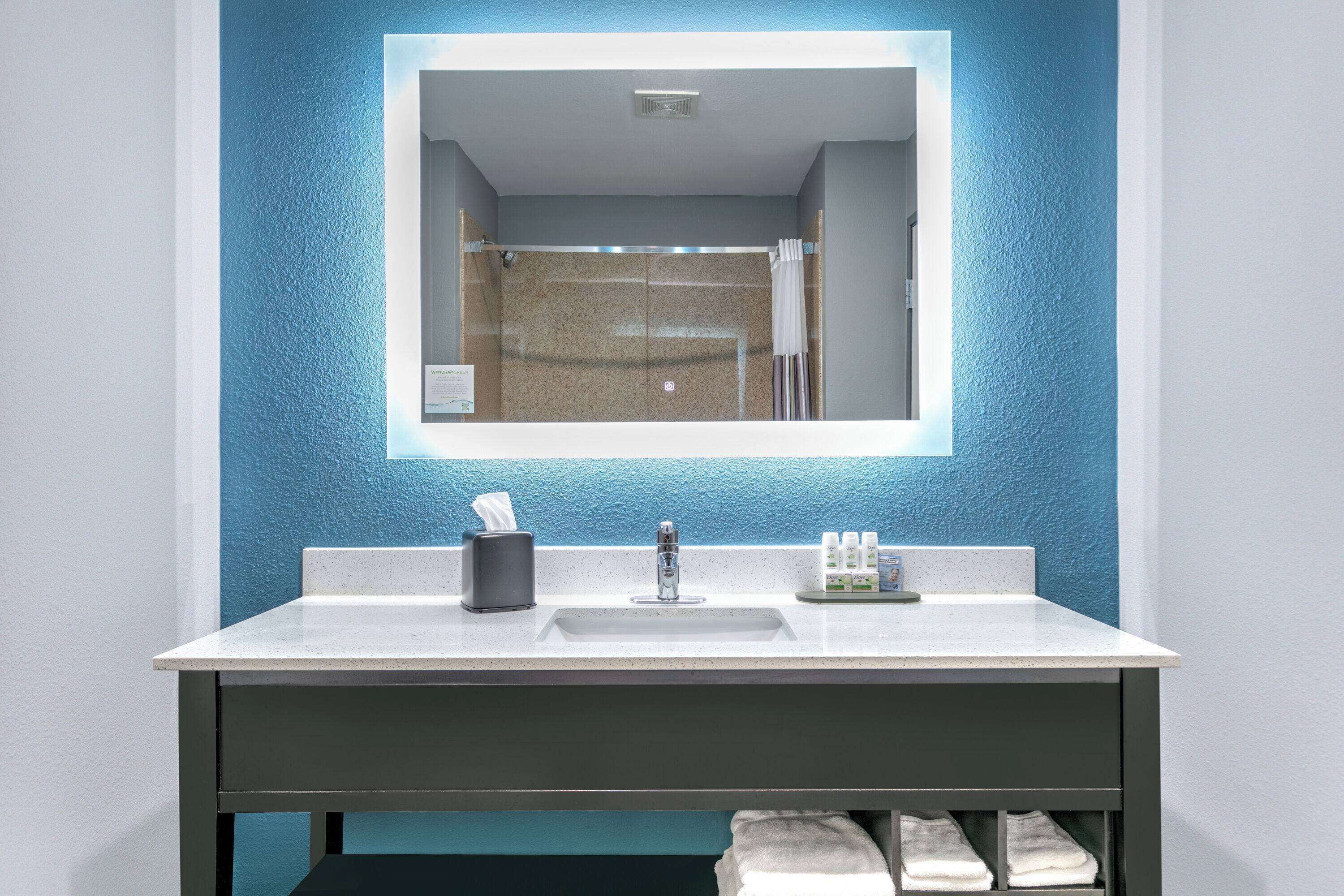 A bathroom with a white sink, a mirror, and a shower area.