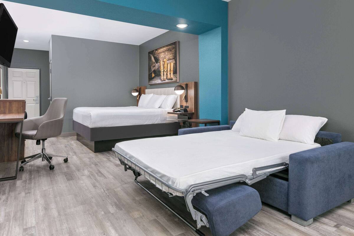 Une chambre d’hôtel avec deux lits, un bureau et une chaise.