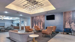 A modern lobby with a central seating area, a dining area, and a large mural on the wall.