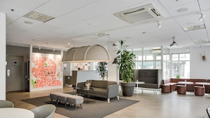 A modern office space with a large map on the wall, a sofa, a coffee table, and a potted plant.