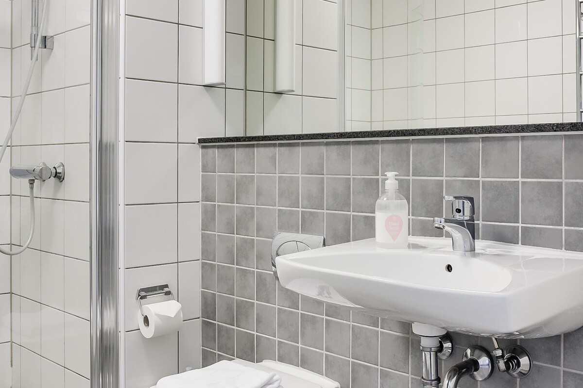 A modern bathroom with a shower, toilet, and sink.