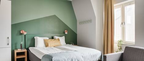 A modern bedroom with a bed, bedside table, and a sofa.