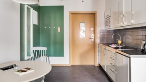 A modern kitchen with a wooden door, a dining area with a table and chairs, and a large window.