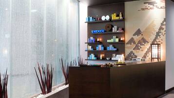 Reception area with a large glass partition offering a view of the lobby, a reception desk and shelves displaying amenities.