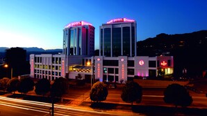 Un hotel con fachada moderna, varios pisos y letreros iluminados.