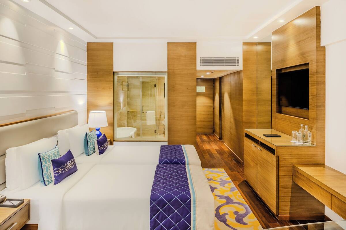 A hotel room with a large bed, a desk, a TV, and a shower area.