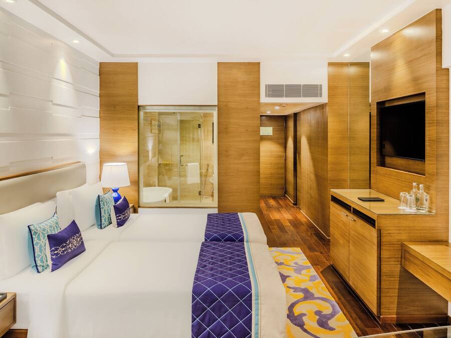 Quarto de hotel com uma cama grande, uma escrivaninha, uma televisão e zona de duche.