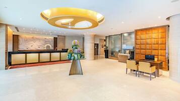 A modern hotel lobby with a reception desk, a decorative centerpiece, and a seating area.