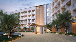 Un hotel moderno con entrada central, varios balcones y un jardín bien cuidado.