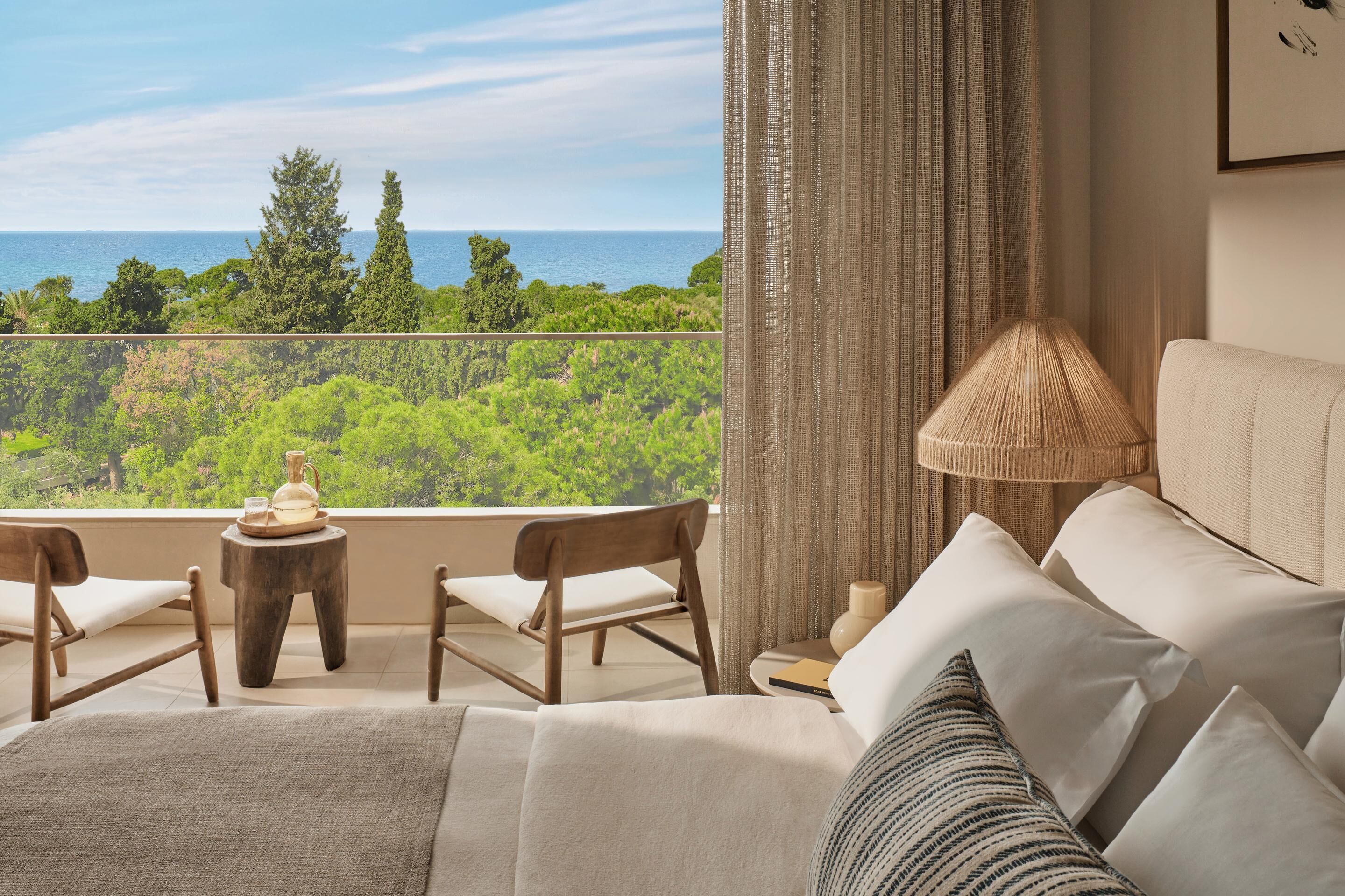 Un balcon avec vue sur la mer, un canapé, une lampe et deux fauteuils.