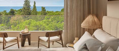 Un balcon avec vue sur la mer, un canapé, une lampe et deux fauteuils.