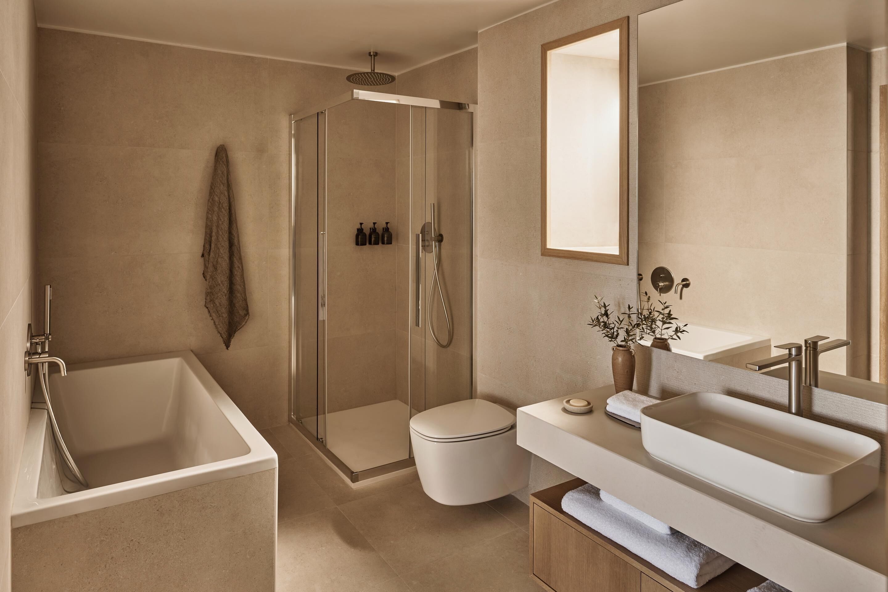 Ein modernes Badezimmer mit bodenebenen Dusche, freistehender Badewanne, Toilette und Waschtisch inklusive Waschbecken und Spiegel.