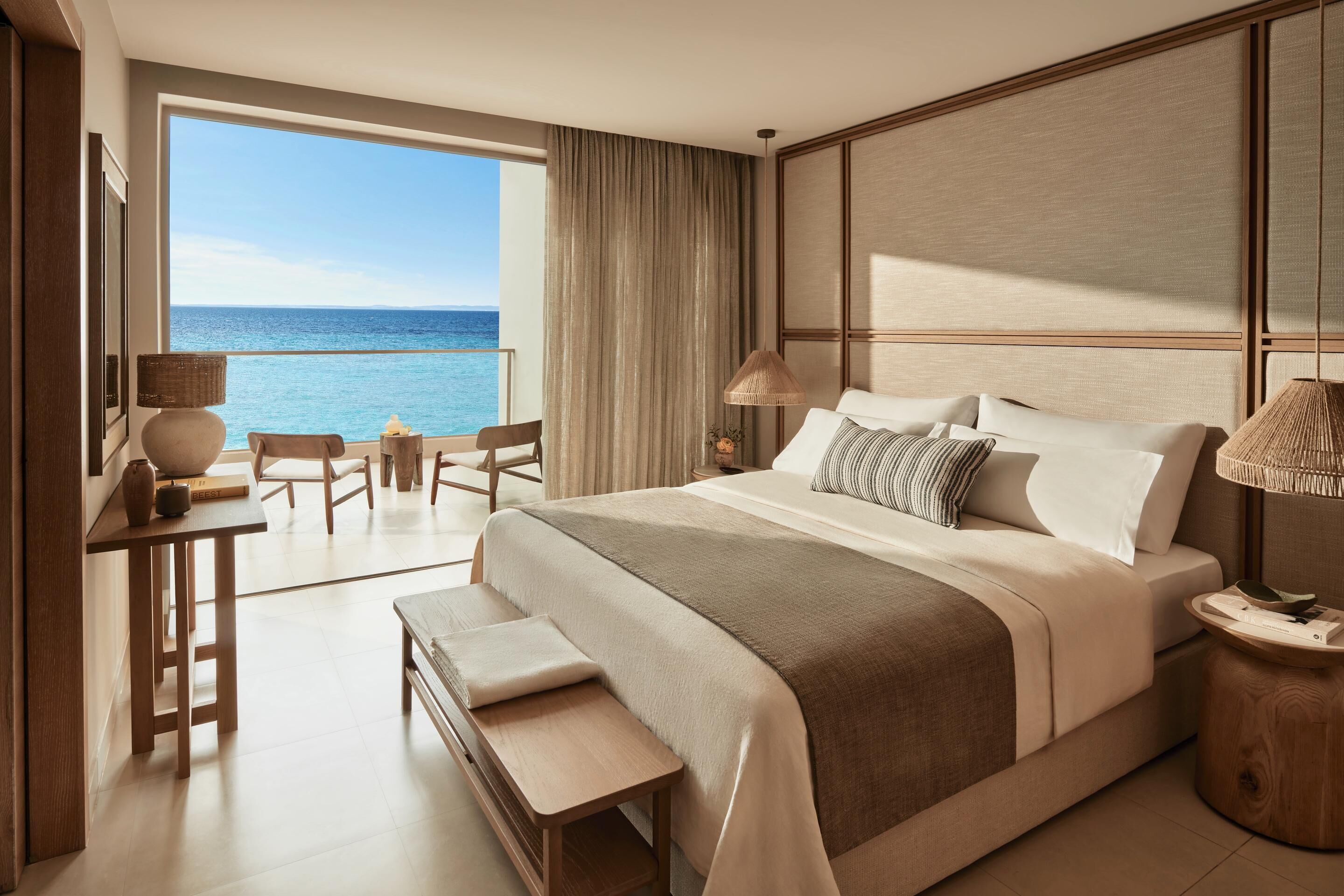Habitación de hotel con una cama grande, un escritorio, una silla y vista al océano.