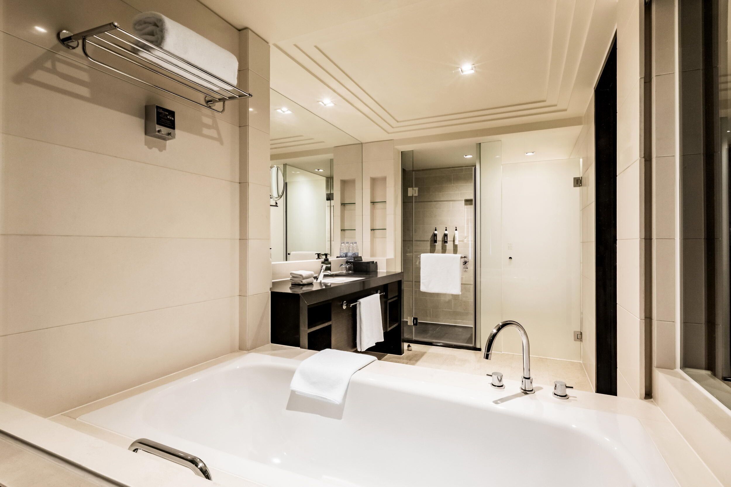 Ein modernes Badezimmer mit einer großen Badewanne, einem Waschtisch mit Spiegel und einer Duschkabine aus Glas.