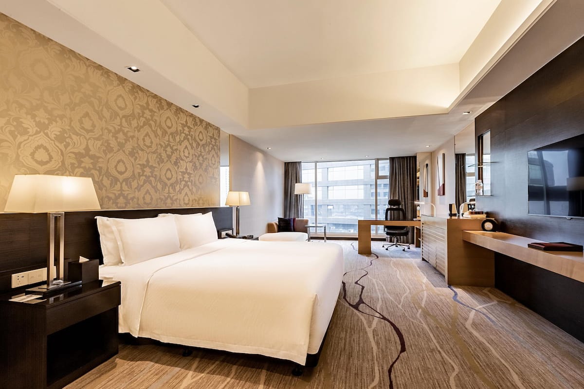 Une chambre d’hôtel moderne équipée d’un grand lit, d’un bureau, d’une chaise et d’un téléviseur.
