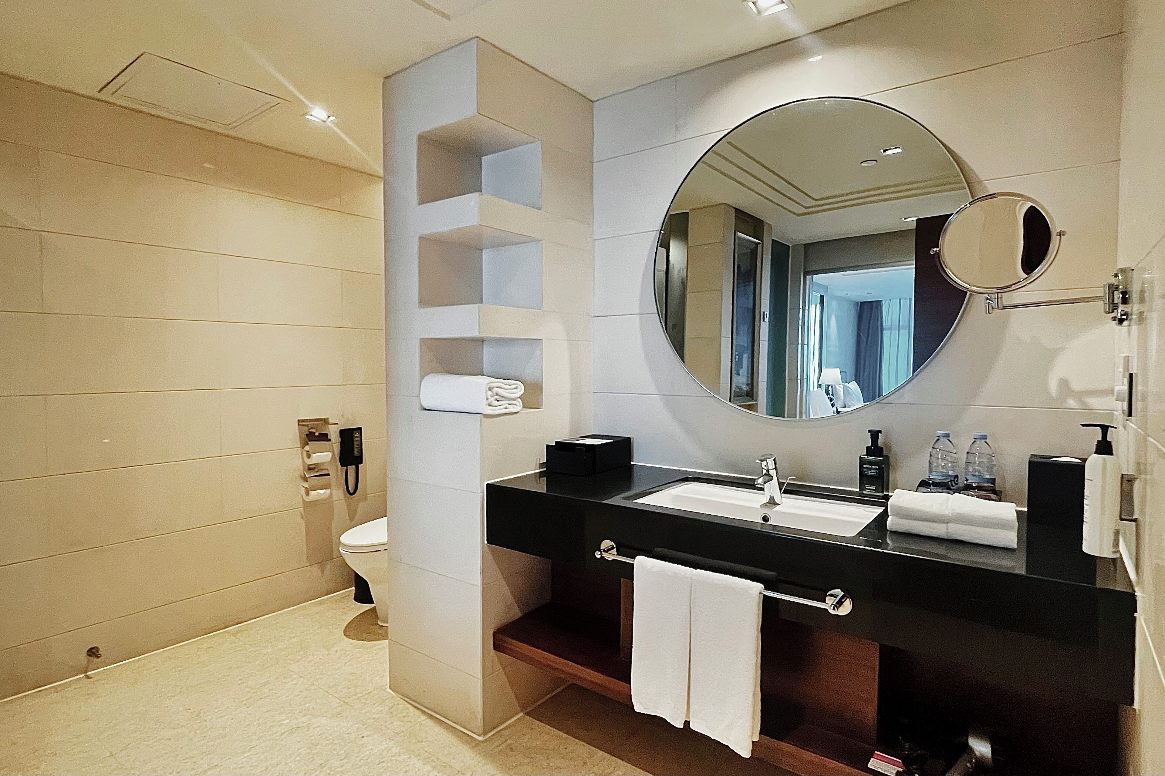 A modern bathroom with a black sink, a large mirror, and a toilet.