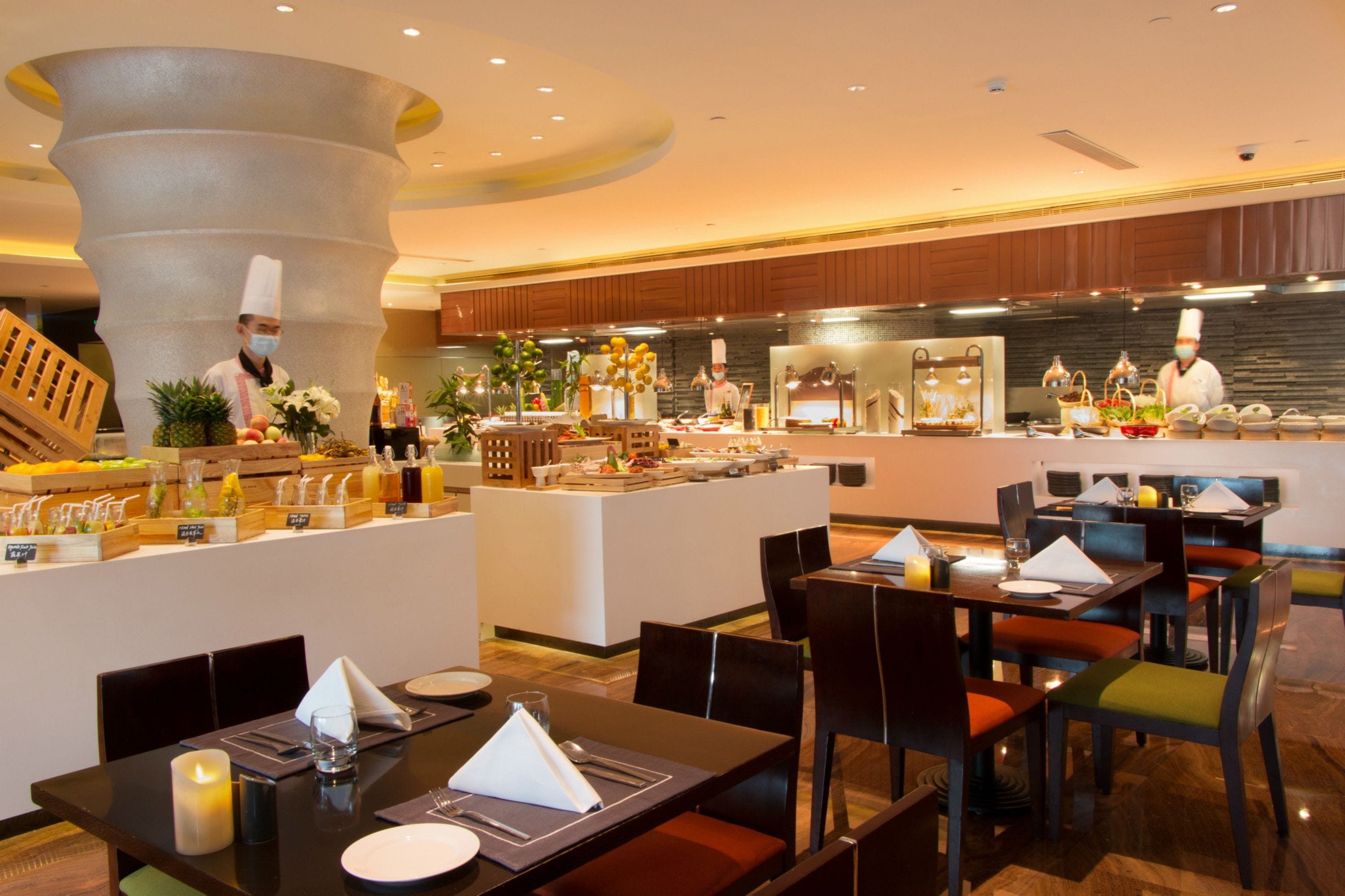 Ein Hotelrestaurant mit einer Buffettheke, mehreren Tischen und einer zentralen Servierstation.