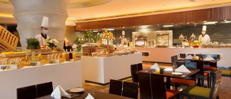 Ein Hotelrestaurant mit einer Buffettheke, mehreren Tischen und einer zentralen Servierstation.