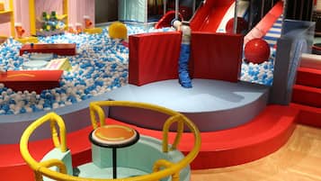 Un espace de jeux pour enfants avec des toboggans, des piscines à balles et des structures ludiques.
