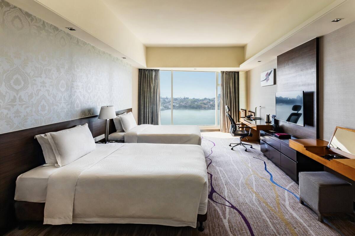 Une chambre d’hôtel avec deux lits, un bureau, une télévision et une vue sur un plan d’eau.