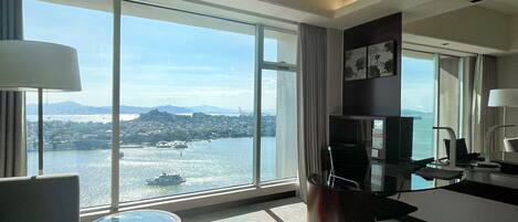 Habitación de hotel moderna con un amplio ventanal que ofrece vistas a la ciudad y al agua.